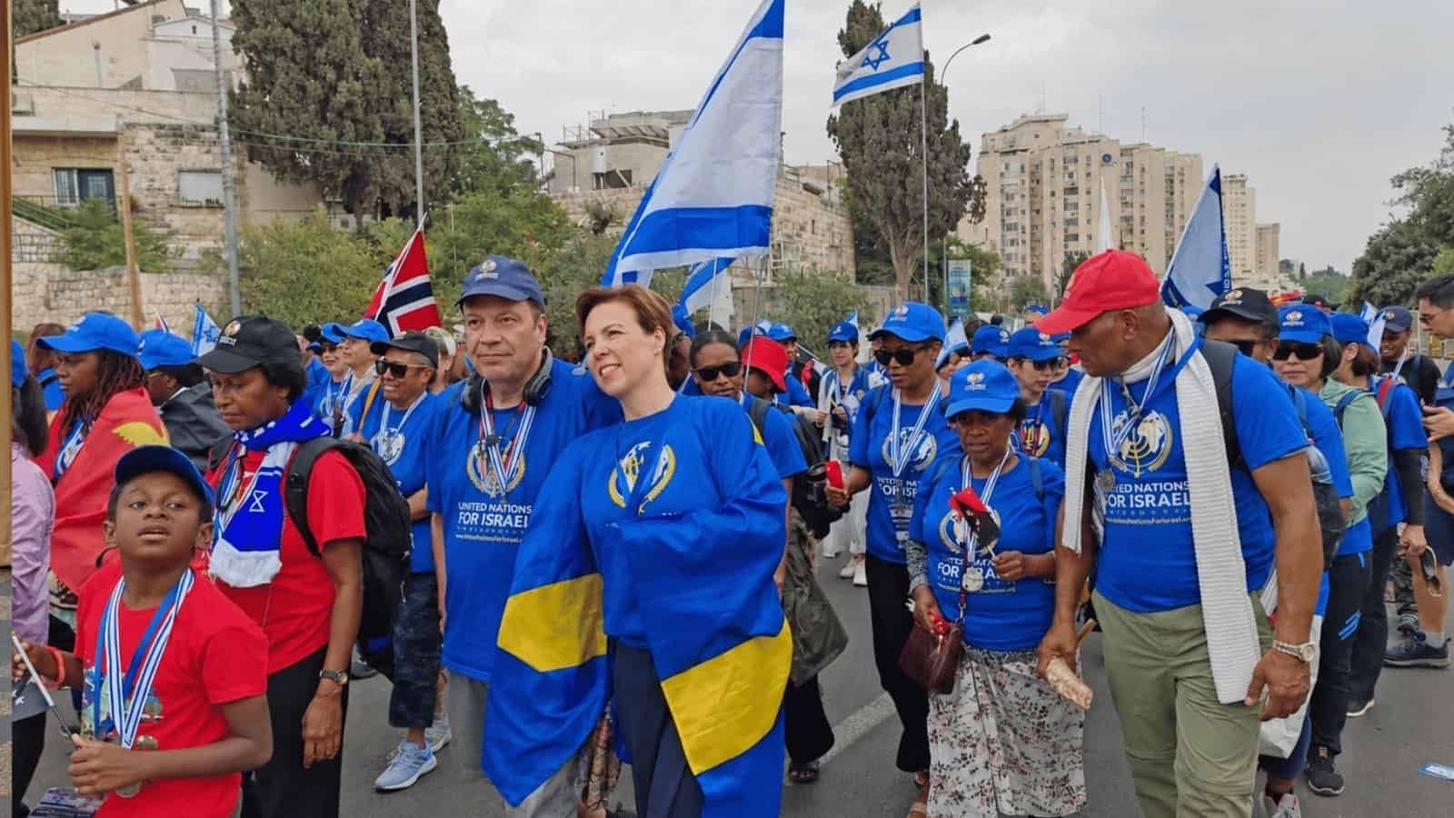 Group of people marching with Israeli flags during a parade or rally.