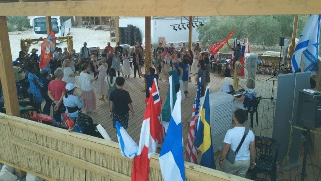 Gathering of people with flags at a political event under a tent.